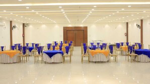 A spacious hall with rows of tables and chairs, a wooden door at the front, and a ceiling with recessed lighting. - Evana Rajaji  (Ganga Bhogpur Malla)