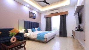 A modern hotel room with a bed, a sofa, a coffee table, and a TV. - Evana Rajaji  (Ganga Bhogpur Malla)