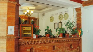 A reception area with a brick counter, potted plants, and a clock on the wall. - Ecohomekathmandu (Nagarjun)