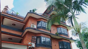 A multi-story building with a brick facade, multiple balconies, and air conditioning units. - Ecohomekathmandu (Nagarjun)