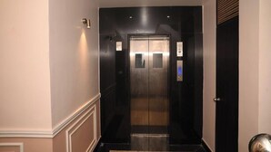 A modern elevator with a metallic finish, a control panel, and a door with a handle. - Hotel Nirvvana Residency (Varanasi)