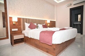 Una habitación de hotel moderna con una cama grande, cabecera de madera y lámparas de noche.