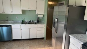Una cucina con mobili bianchi, un frigorifero in acciaio inossidabile e una lavastoviglie.