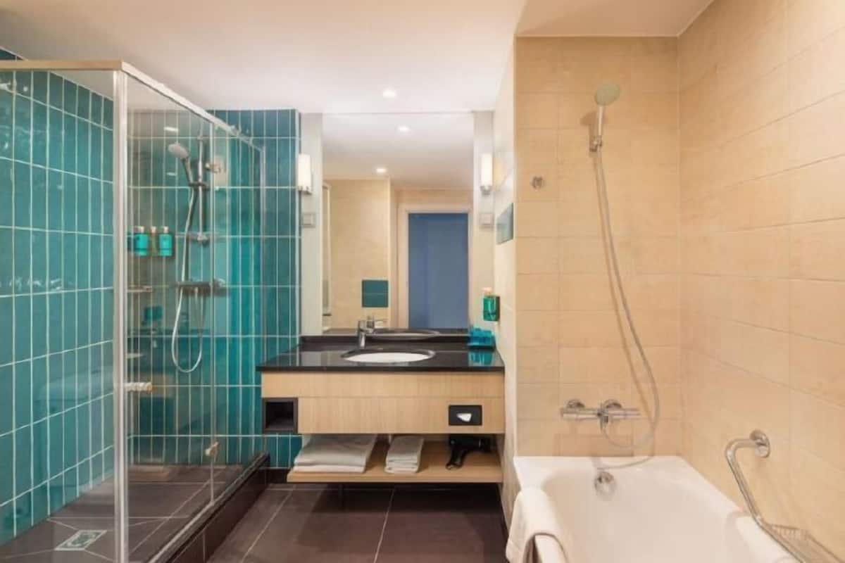 A modern bathroom with a glass-enclosed shower, a bathtub, and a vanity with a sink.