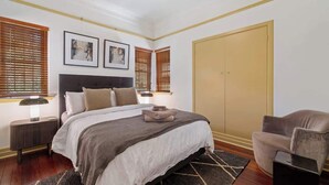Ein Schlafzimmer mit Bett, Nachttischen, einem Kleiderschrank und einem Sessel.