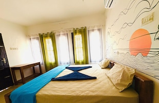 Una habitación de hotel con cama, cortinas, un escritorio y una pared con un mural.