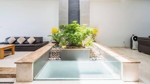 A modern living room with a glass coffee table, a black sofa with beige cushions, and a small wooden table. - ZEN Villa Garden in Thao Dien Ho Chi Minh (Ho Chi Minh City)
