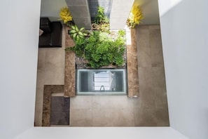 A modern interior with a built-in planter with greenery, a glass partition, and a tiled floor.