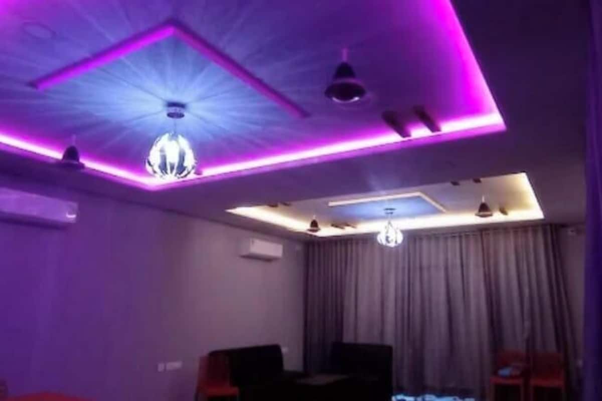 Une pièce dotée d’un plafond au design moderne, avec des spots encastrés et un lustre.