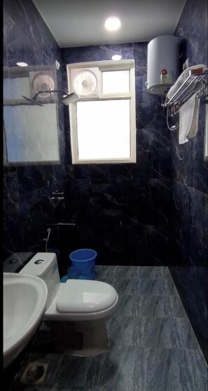 A bathroom with a toilet, sink, and a window. - Uphar Homestay - Hotel & Restaurant (Jaipur)