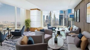 A modern hotel lobby with a panoramic city view, comfortable seating, and a large plant. - voco DUBAI by IHG (Dubai)