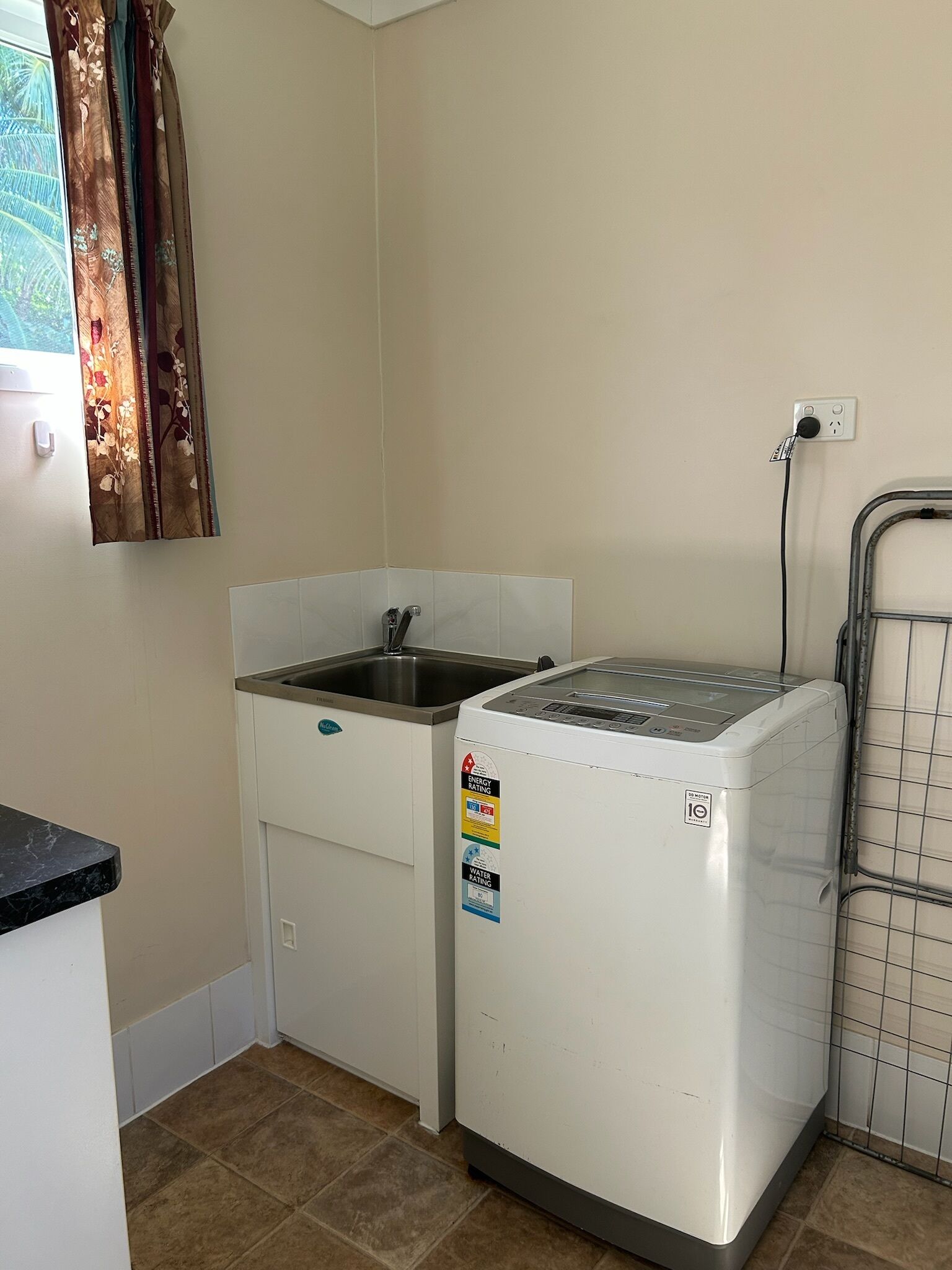 A compact kitchen with a washing machine, a sink, and a tiled floor.