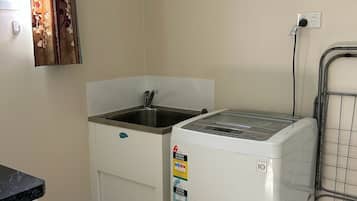 A compact kitchen with a washing machine, a sink, and a tiled floor.