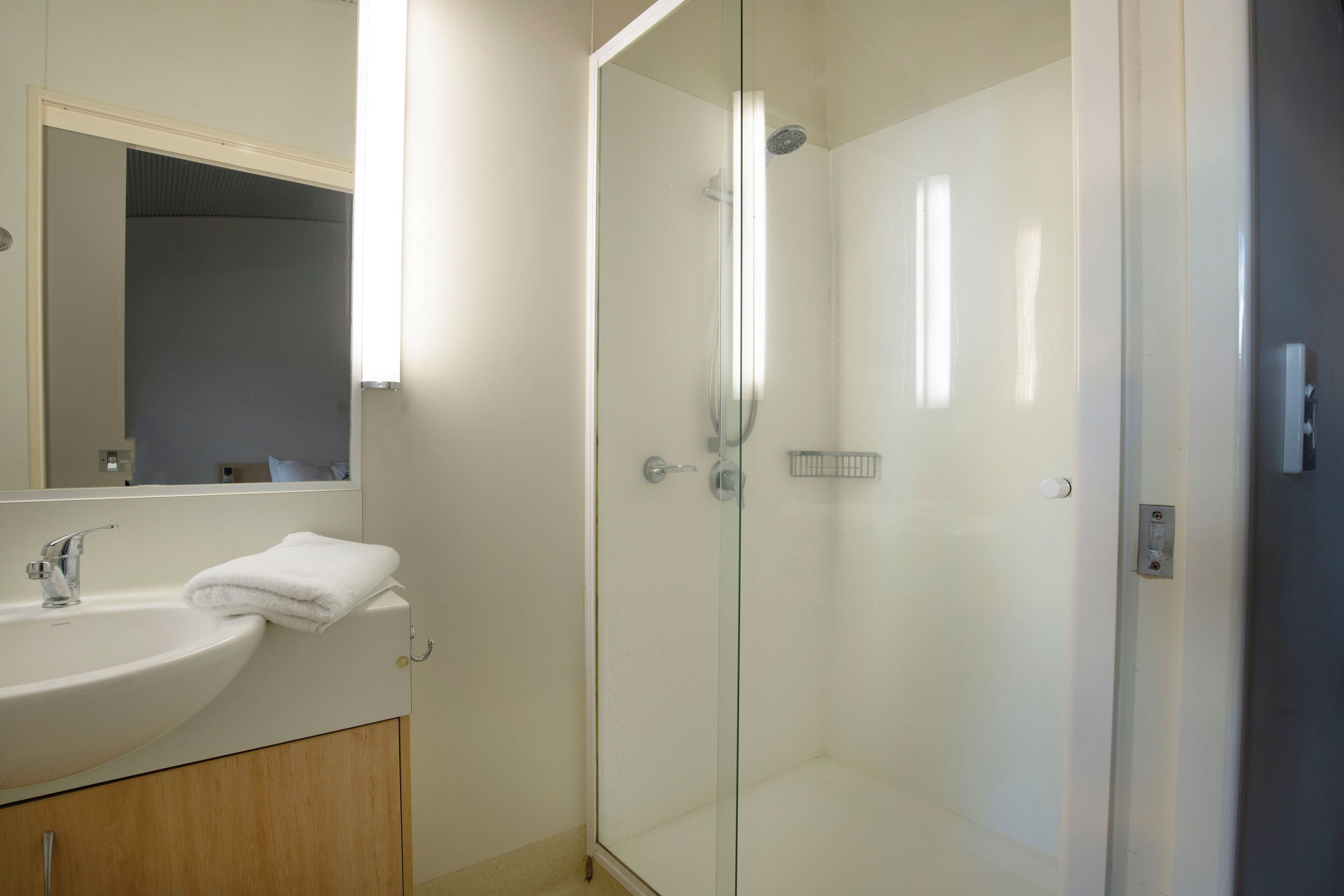 A modern bathroom with a glass-enclosed shower, a white sink, and a mirror above the sink.