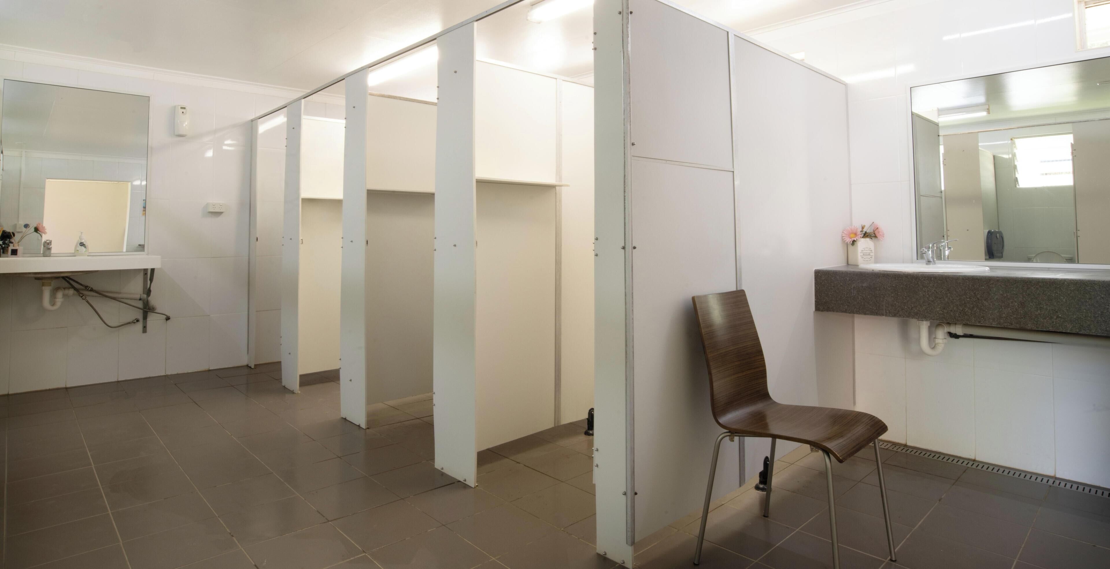 Une salle de bain moderne avec un lavabo, un miroir et une chaise.