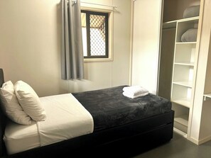 Una camera da letto con un letto, una finestra con tende e un armadio a muro.