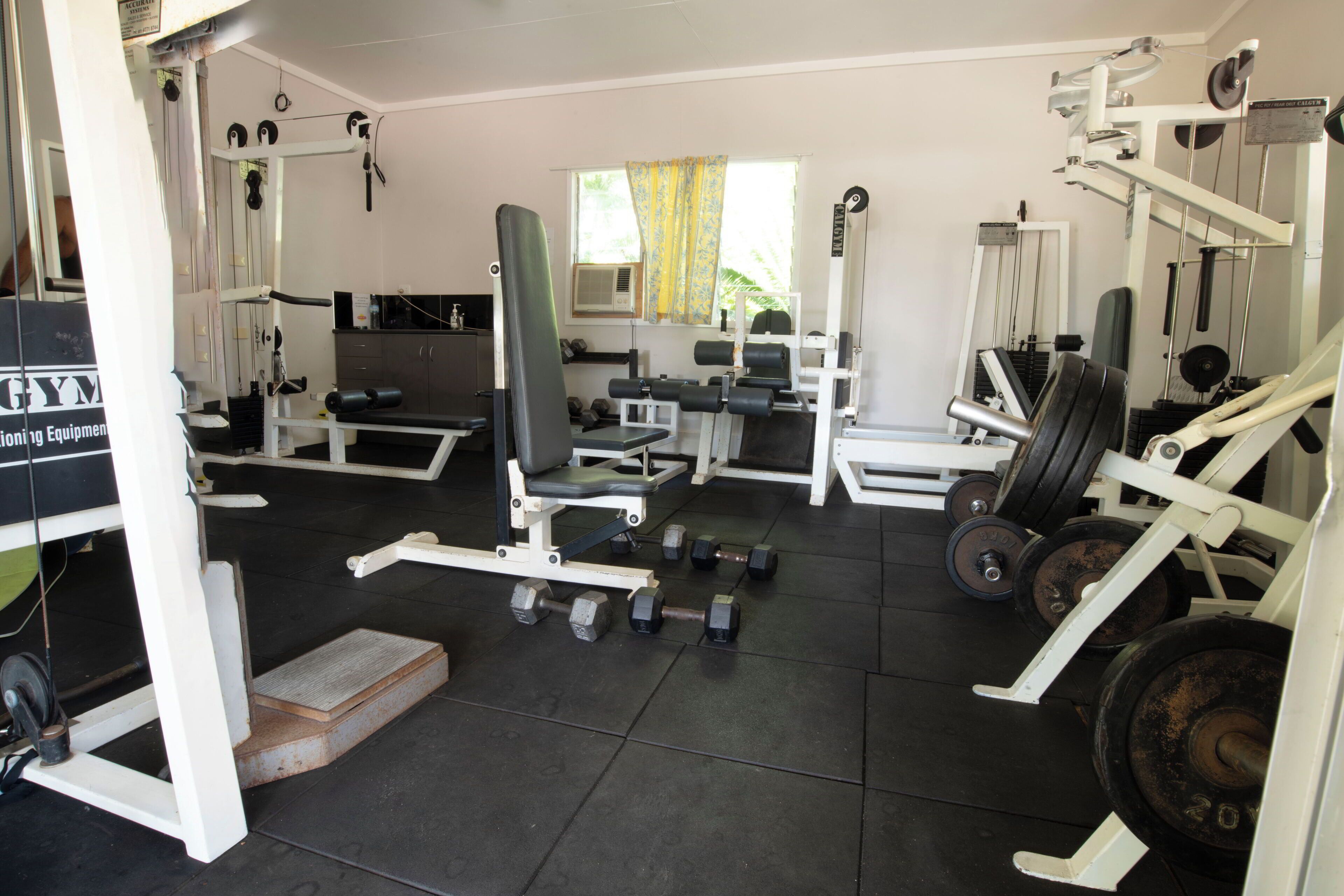 A gym with various exercise equipment, including dumbbells, benches, and weight machines.