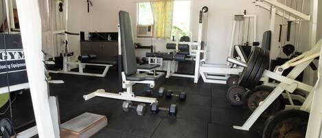 A gym with various exercise equipment, including dumbbells, benches, and weight machines.