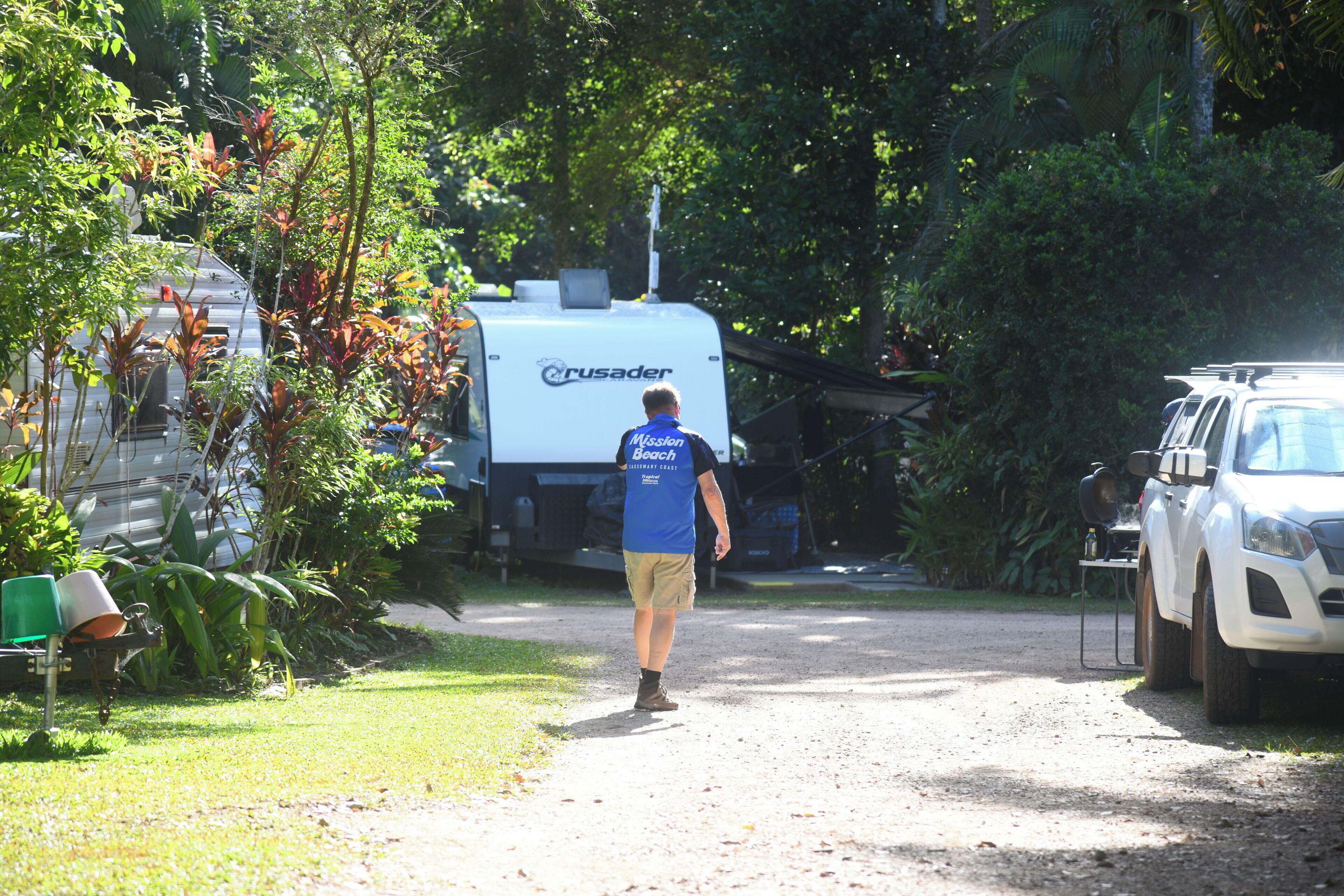 A man walking on a dirt path towards a white Crusader RV.