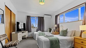 A hotel room with two beds, a TV, a desk, and a chair. - Sunny Hilltop Red Bach w Lake and Mountain Views (Taupō)