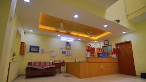 A reception area with a wooden desk, a sofa, and a ceiling fan. - Nalli Plaza (Omalur)