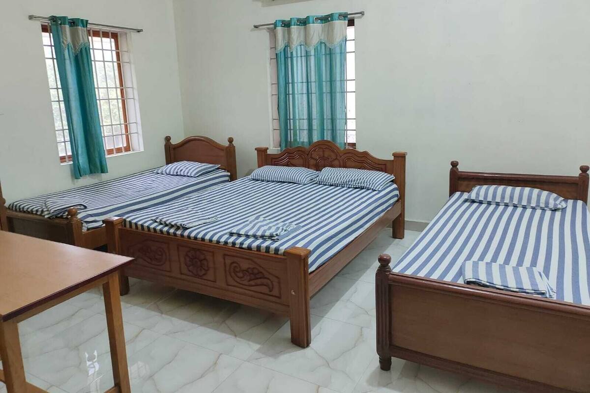 A room with two wooden beds, a wooden table, and a window with curtains.
