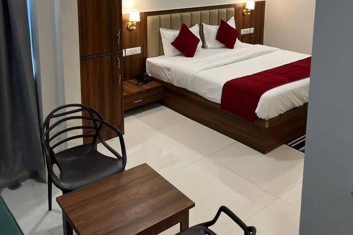 A hotel room with a bed, bedside table, chair, and a small table.