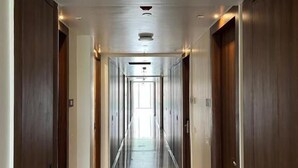 A long, narrow hallway with wooden doors on both sides and a tiled floor. - KRISHNA ANANDAM PALACE (Mathura)