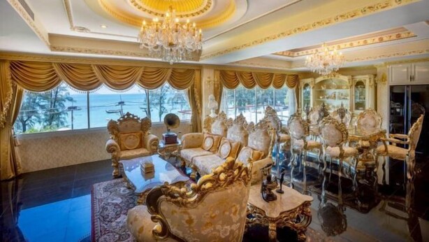 Una habitación lujosa con muebles ornamentados, una araña y ventanas amplias que ofrecen una vista.