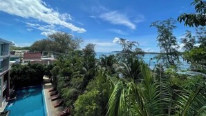 Zona de piscina con sillones de descanso, rodeada de exuberante vegetación tropical y vistas al mar.