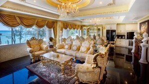 Una habitación lujosa con muebles ornamentados, un candelabro y vista al mar.