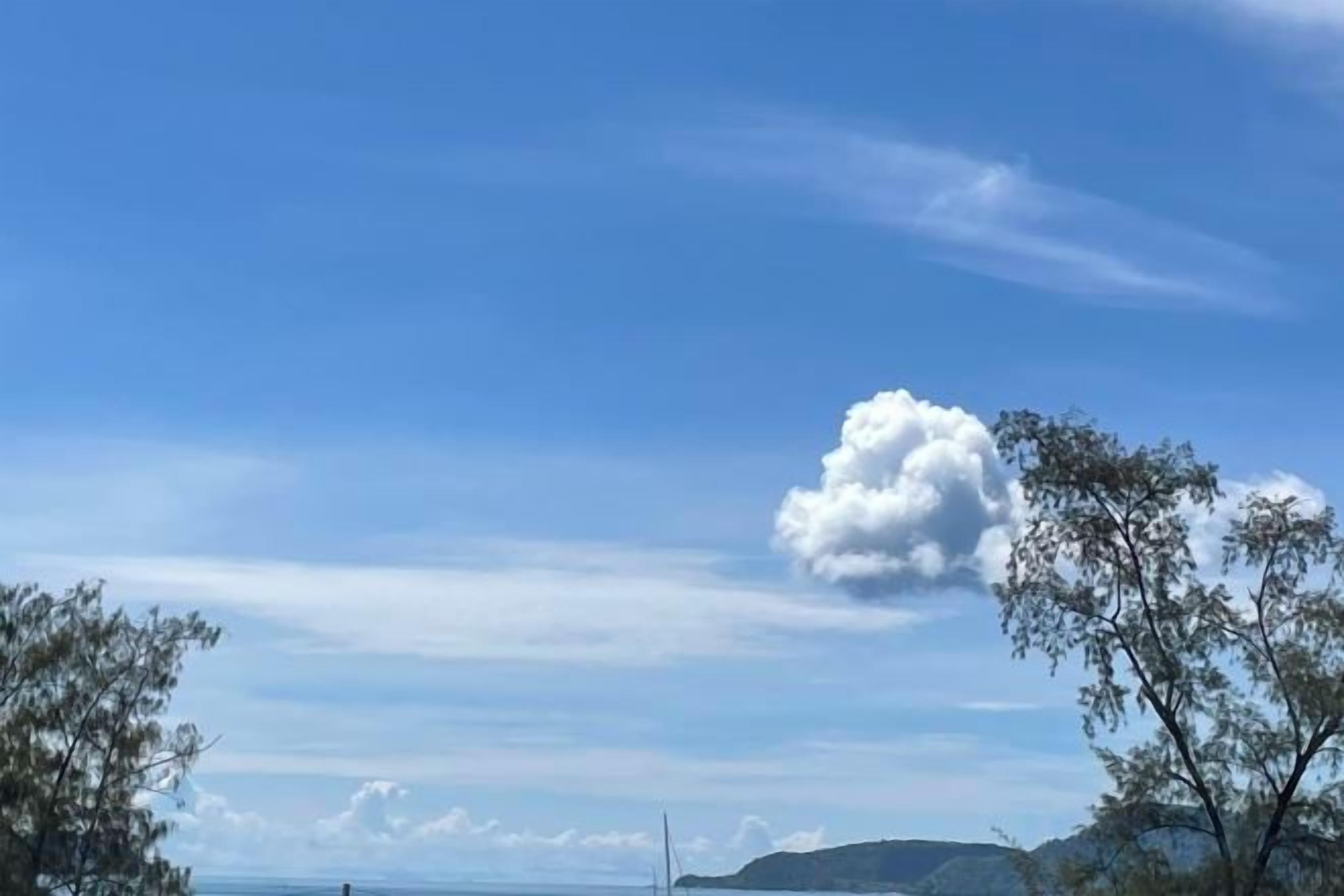 Un ciel dégagé avec un seul nuage et des reliefs terrestres visibles au loin.