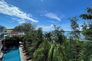 A pool surrounded by lush greenery and a clear view of the sea. - Two Bedrooms Penthouse Seaview Rawai Beach Phuket (Phuket)