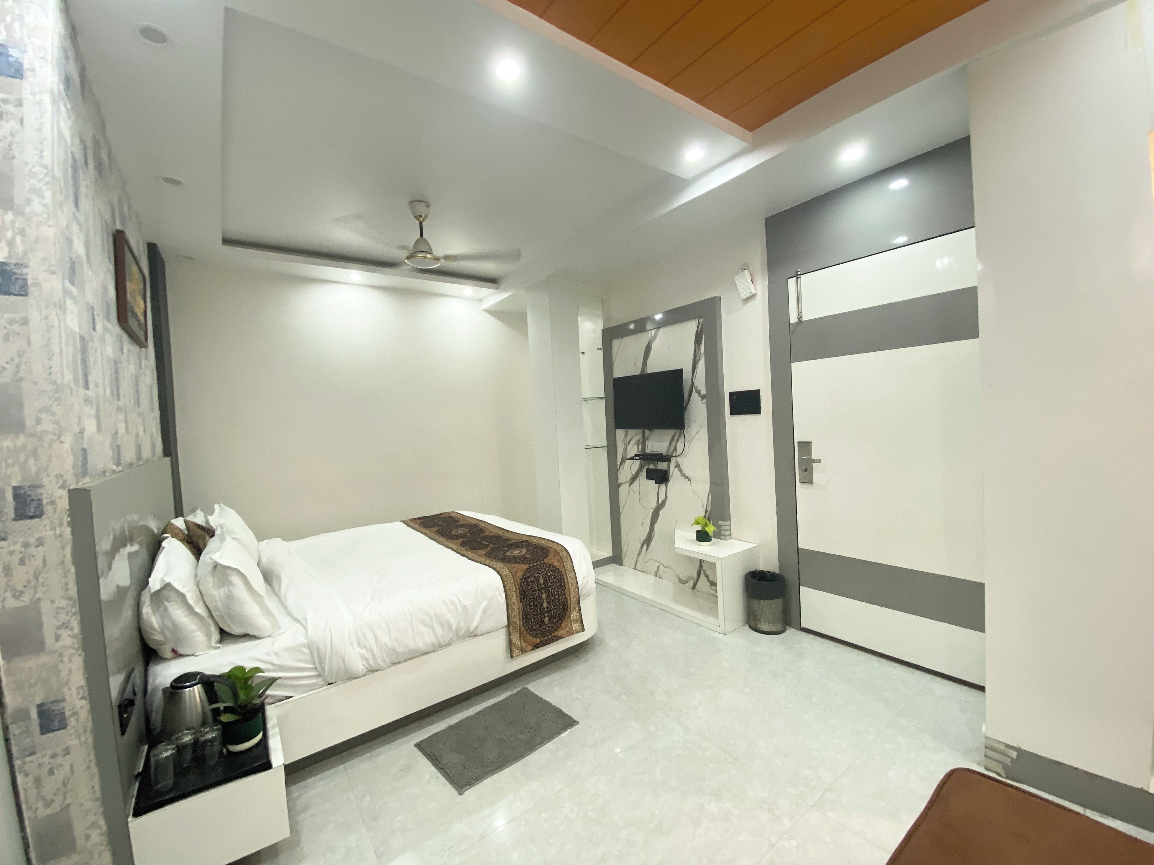Un dormitorio moderno con cama, ventilador de techo, televisor montado en la pared y armario.