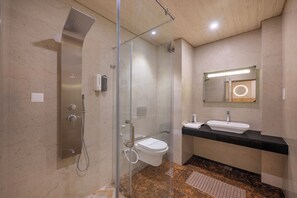 Een moderne badkamer met een douchecabine van glas, een wit toilet en een zwart aanrecht met een wastafel.