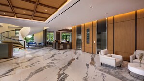 A modern lobby with a marble floor, a curved staircase, and a reception desk. - Oakwood Yogyakarta (Yogyakarta)