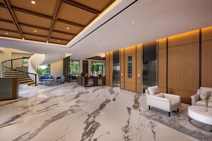 Un vestíbulo moderno con suelo de mármol, una escalera curva y un mostrador de recepción.