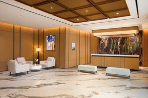 A lobby with a reception desk, seating area, and a marble floor. - Oakwood Yogyakarta (Yogyakarta)