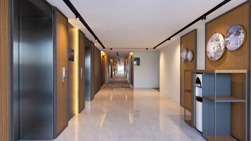 A modern hallway with a long corridor, wooden paneling on the walls, and a water dispenser on the right.