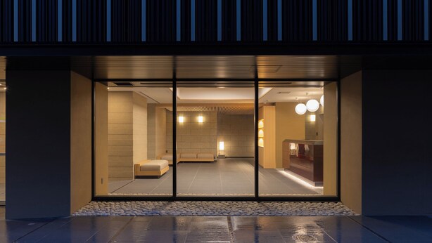 A modern building with a glass entrance, interior lighting, and a stone pathway leading to the entrance. - Mimaru Tokyo Kinshicho (Tokyo)