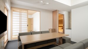 A modern hotel room with a wooden dining table, grey sofas, and a large sliding door leading to a bathroom. - Mimaru Tokyo Kinshicho (Tokyo)