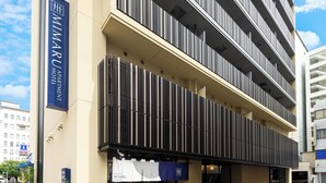 A modern building with a sign for the Minaru Apartment Hotel. It features a vertical striped facade and multiple balconies. - Mimaru Tokyo Kinshicho (Tokyo)