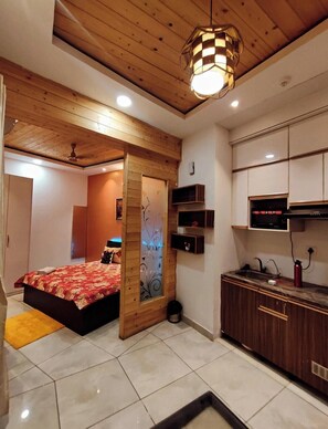 Una camera da letto moderna con un letto, un soffitto in legno e un angolo cottura.