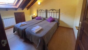 A bedroom with two beds, a skylight, a radiator, and a wooden ceiling. - Casa Carmen for 8-9 people in Biedes (Biedes)
