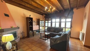 A cozy living room with a fireplace, wooden ceiling beams, a sofa, and a TV. - Casa Carmen for 8-9 people in Biedes (Biedes)