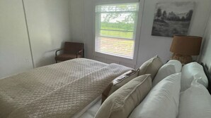 Une chambre à coucher avec un lit, une chaise, une fenêtre et une lampe.