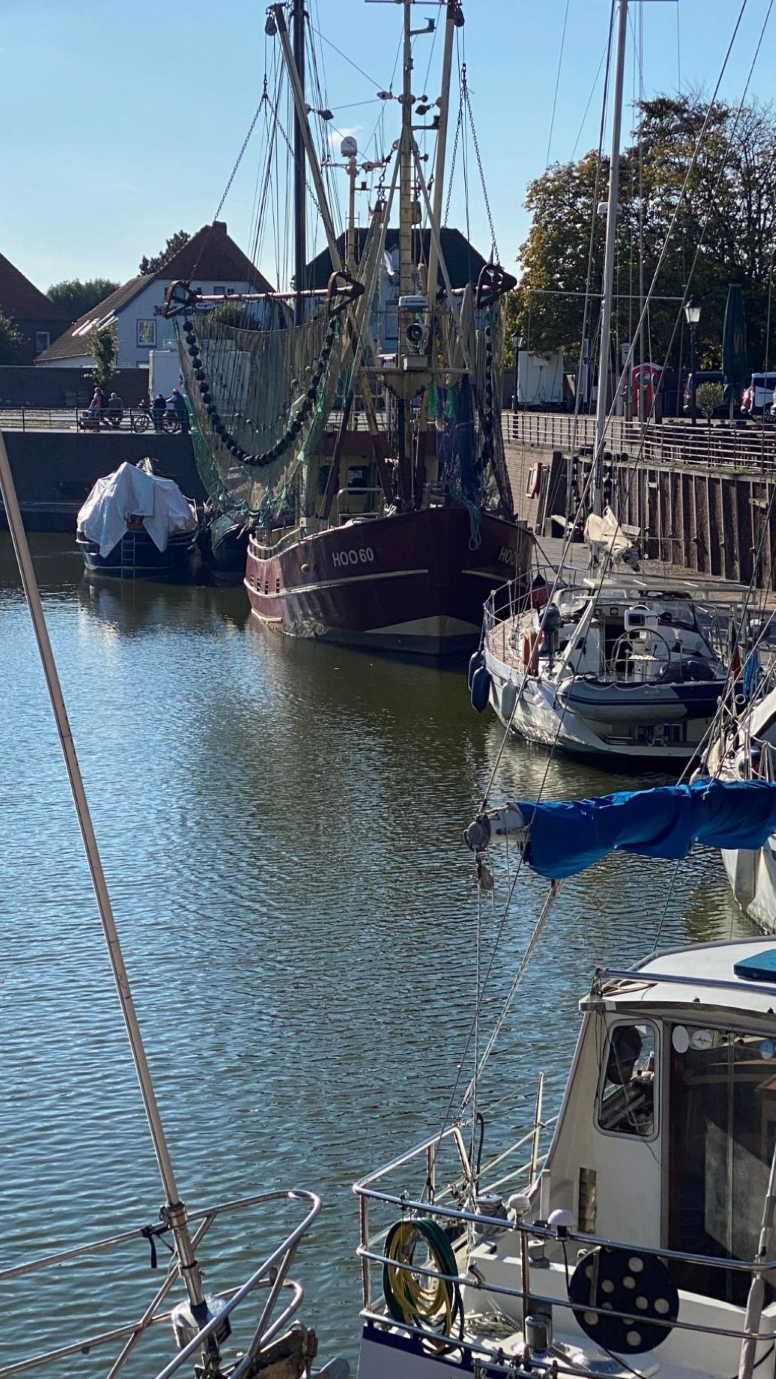 A marina with several boats docked, including a large fishing vessel and smaller boats.