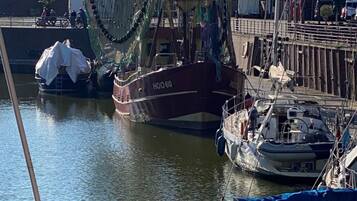 A marina with several boats docked, including a large fishing vessel and smaller boats.