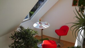 Een modern interieur met een ronde tafel, twee rode stoelen, een potplant en een trap.