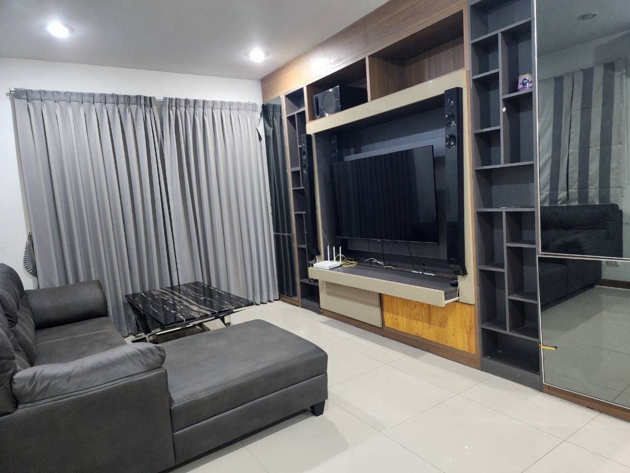 A living room with a sofa, a coffee table, a TV, and built-in shelving.